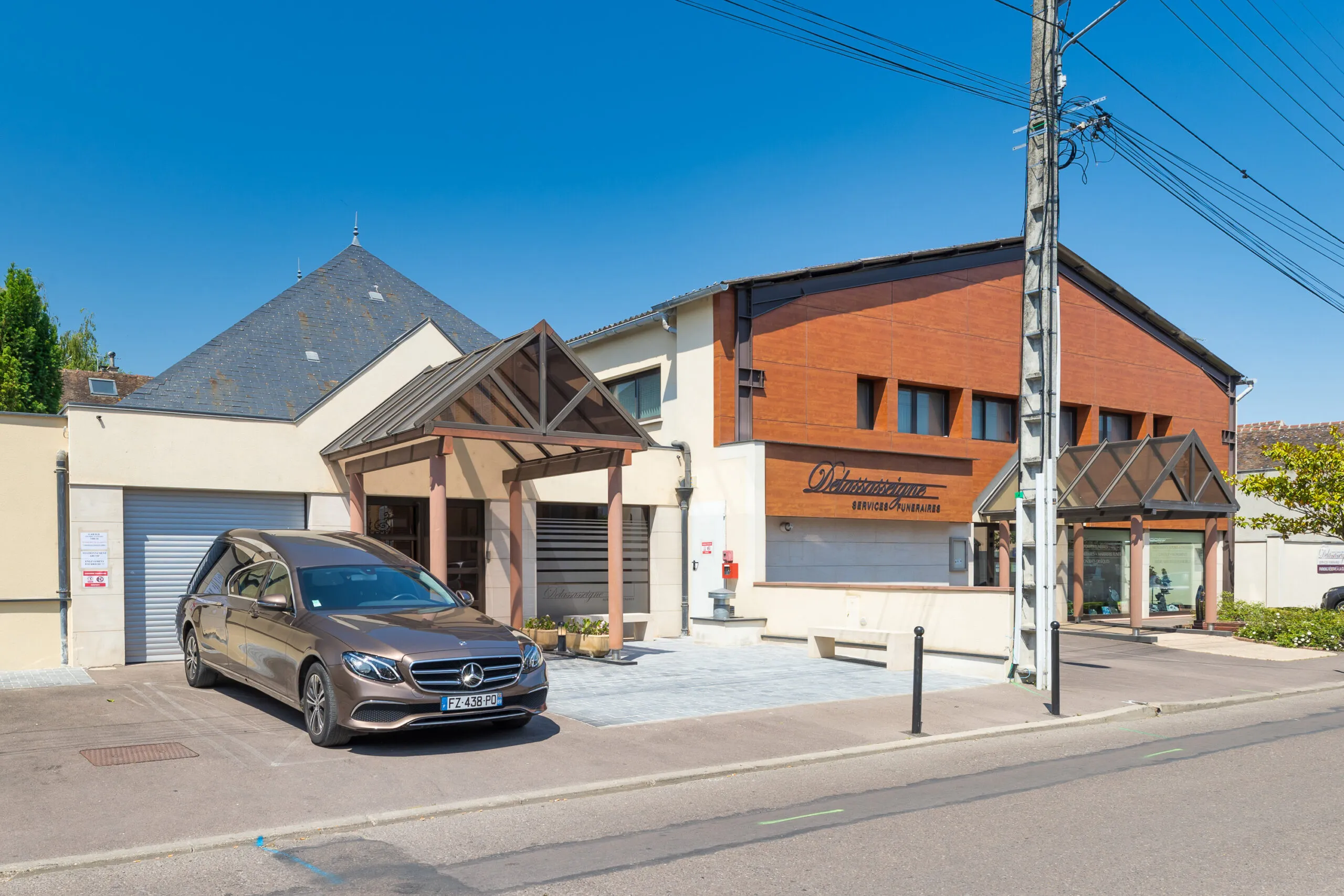 Façade de l'agence des Services Funéraires Delassasseigne avec corbillard Mercedes stationné devant le funérarium