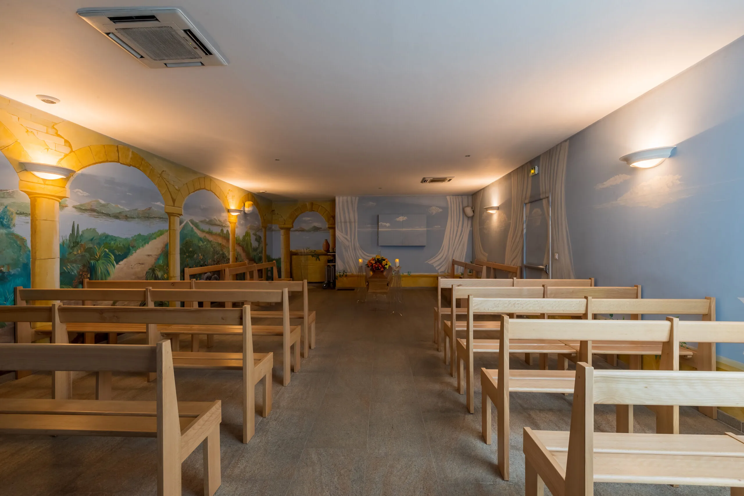 Salle de cérémonie des Pompes Funèbres Gattot avec bancs en bois et fresques murales peintes