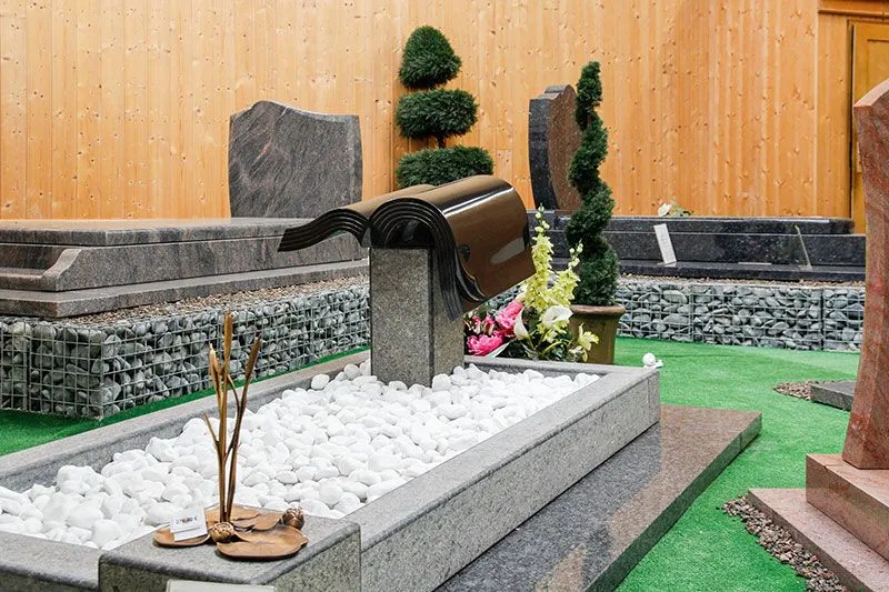 Monument funéraire en granit personnalisé avec stèle en forme de livre ouvert et galets blancs